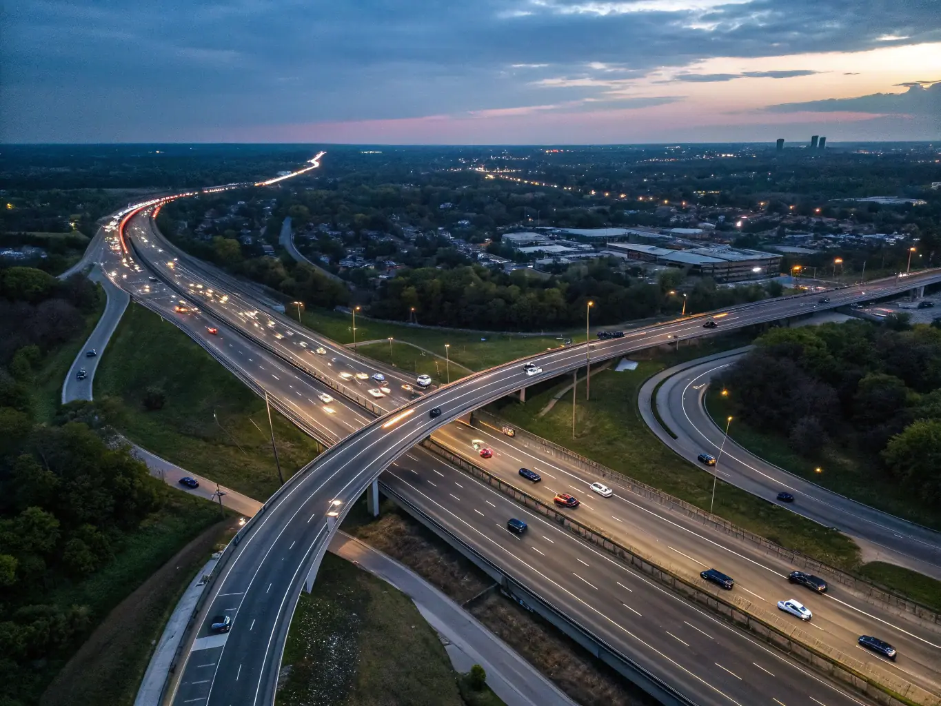 A high-angle, wide shot of a modern highway interchange at dusk, showcasing Surya's infrastructure development capabilities. The image should convey efficiency and connectivity.